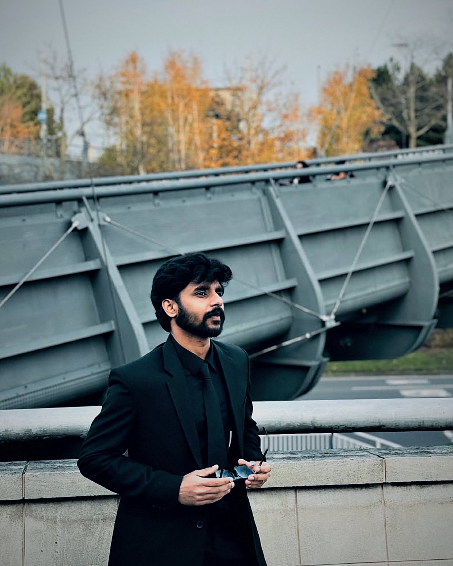 Arun holding his sunglasses, looking into the distance